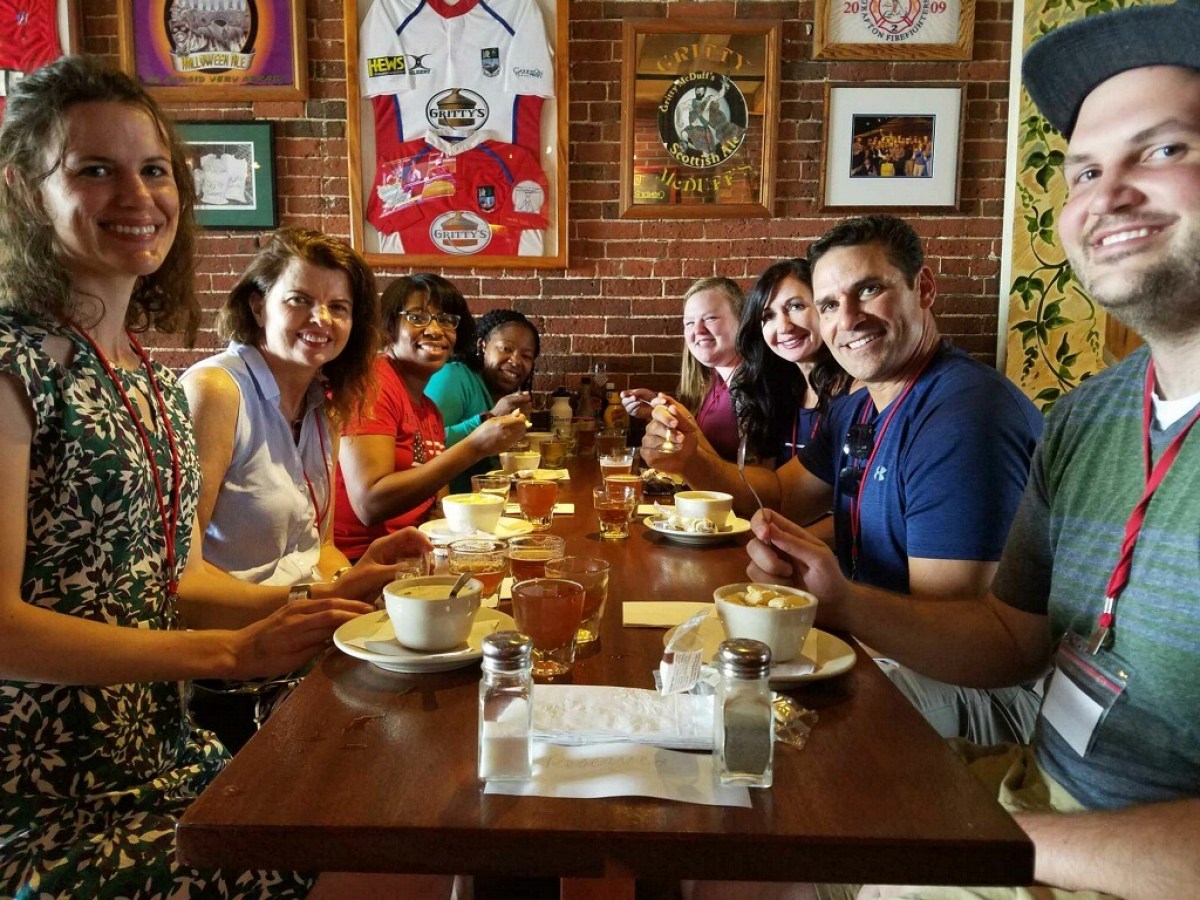 a group of people sitting at a table eating seafood chowder