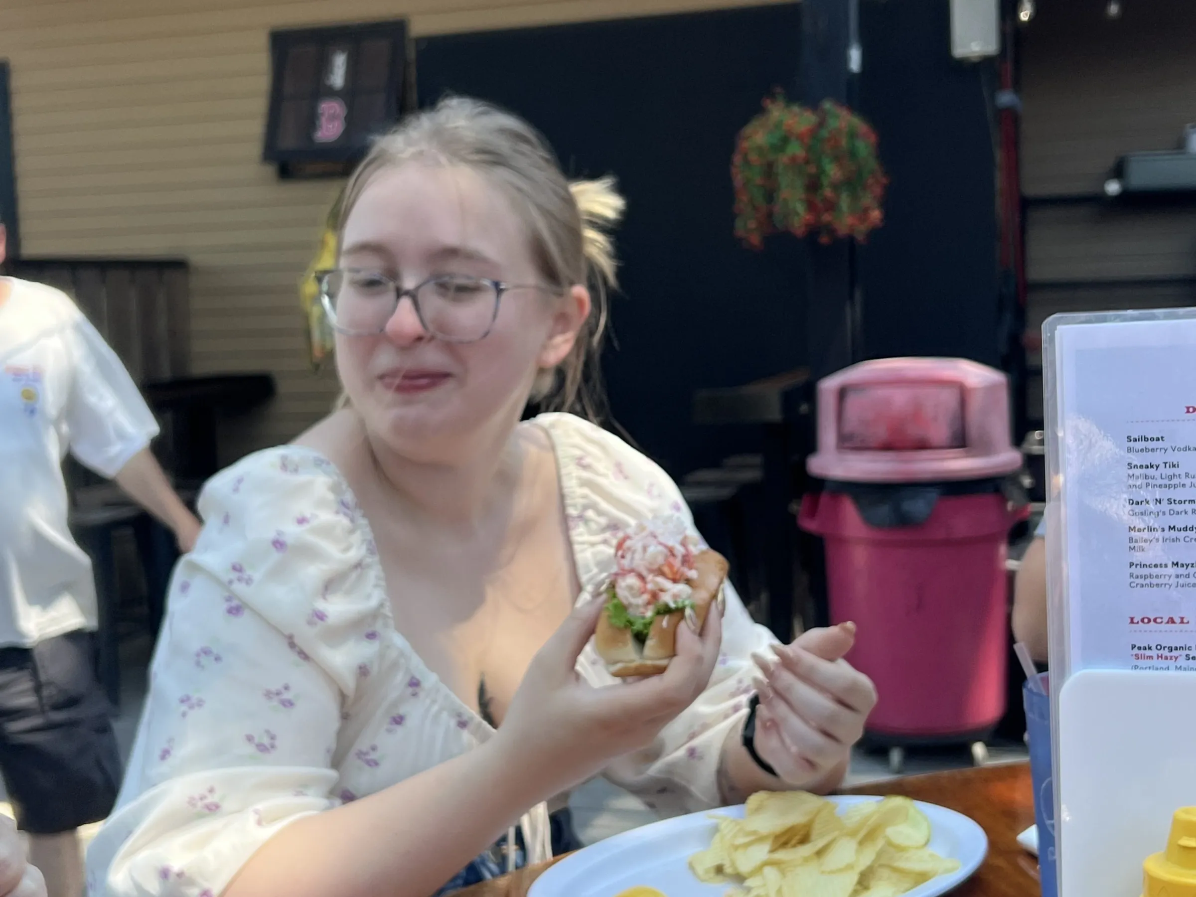 Person eating at an outdoor table with a plate of food.