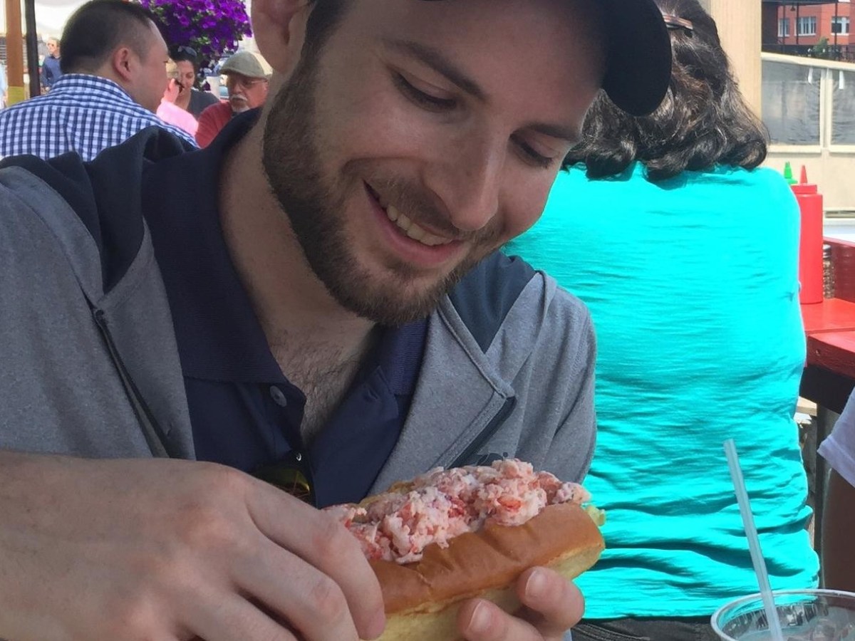 man smiling and eating lobster roll