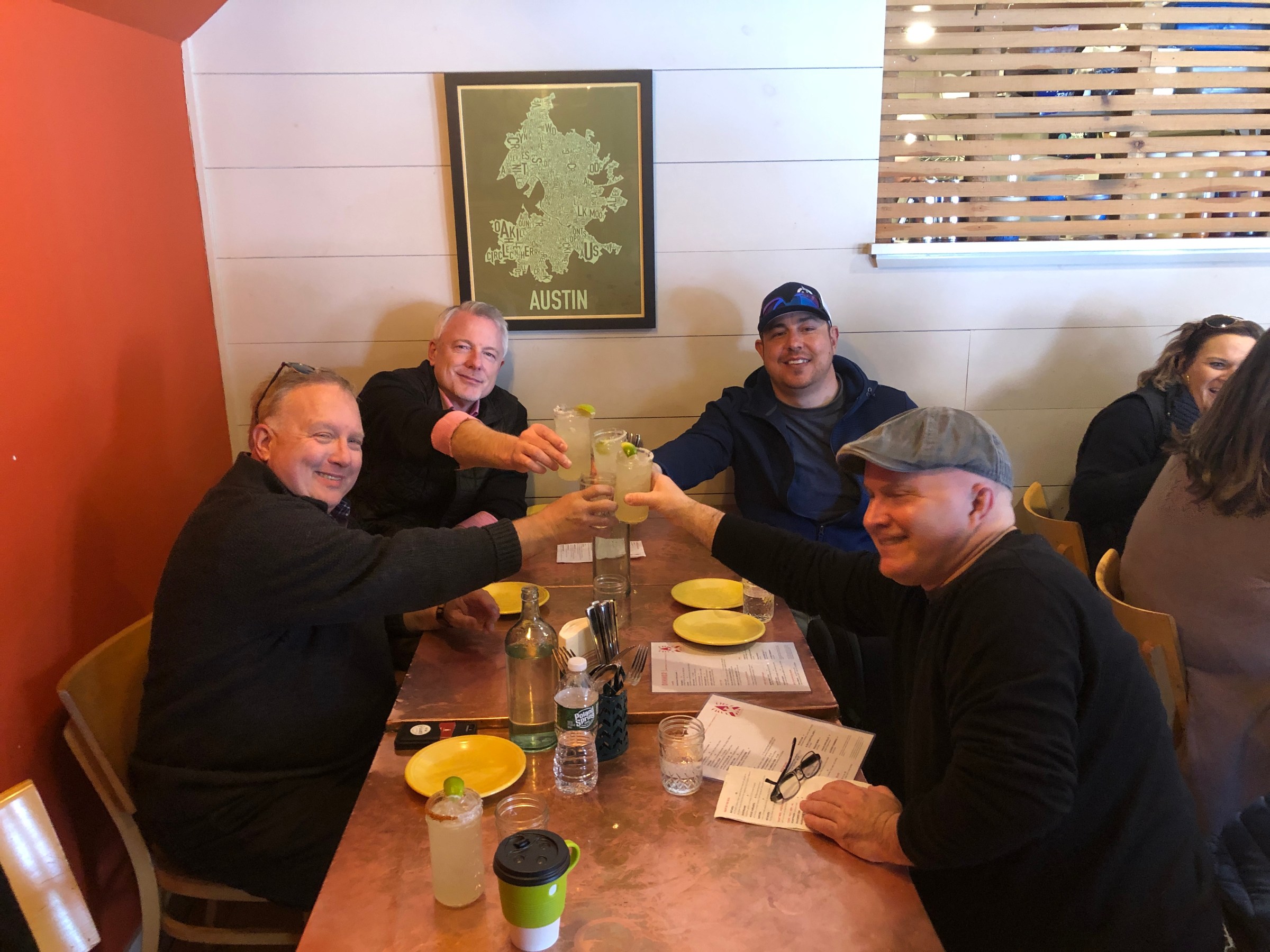 a group of people sitting at a table with margarita glasses