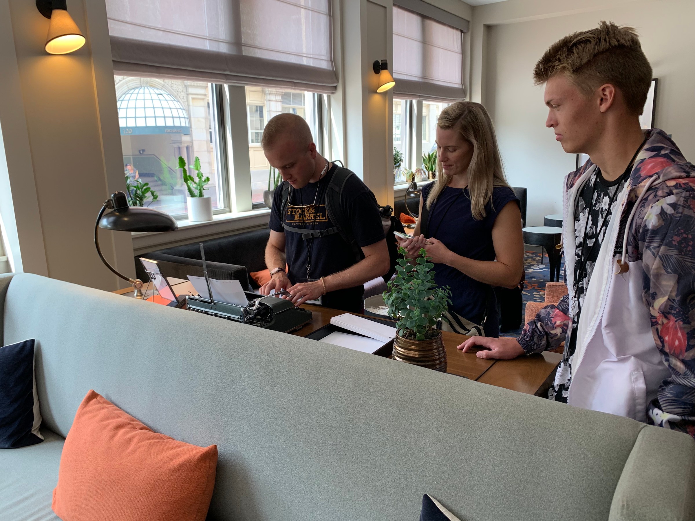 a group of people standing at a table using a typewriter