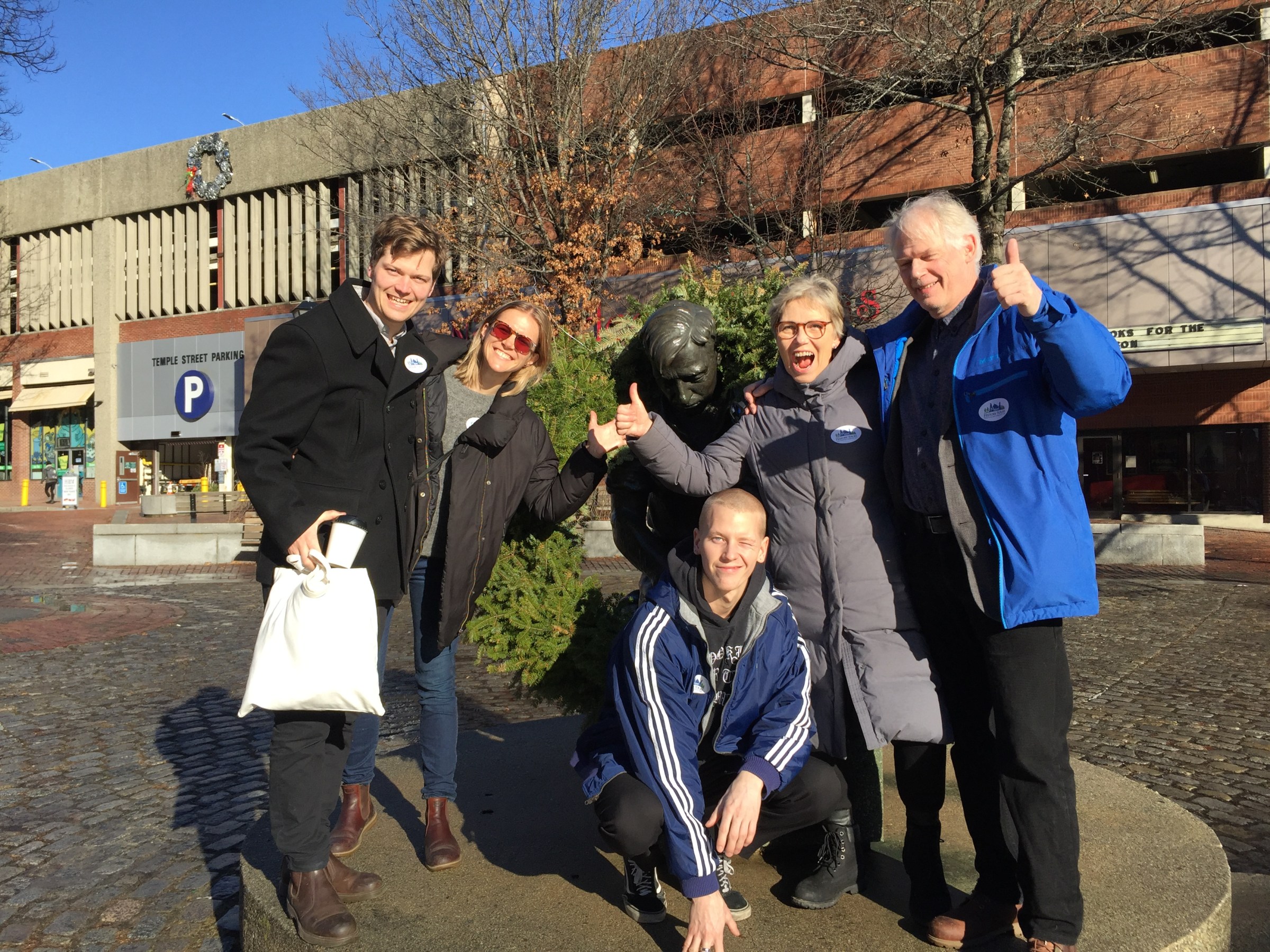 group of people posing by a statue for a photo