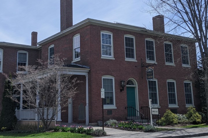a large brick building with grass in front of a house