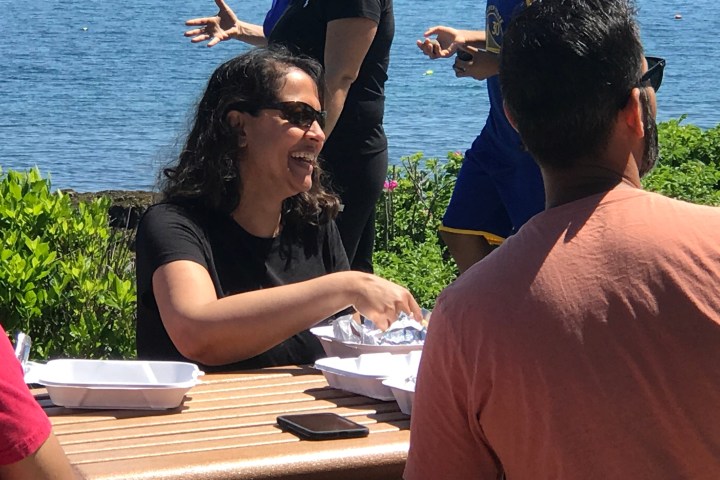 a group of people sitting on a bench next to a body of water
