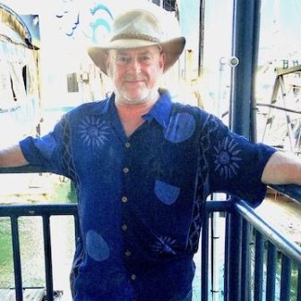 Edward Woodward standing in front of a fence