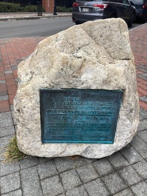 a stone building that has a sign on a brick sidewalk