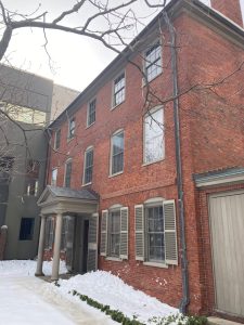 a house covered in snow in front of a brick building