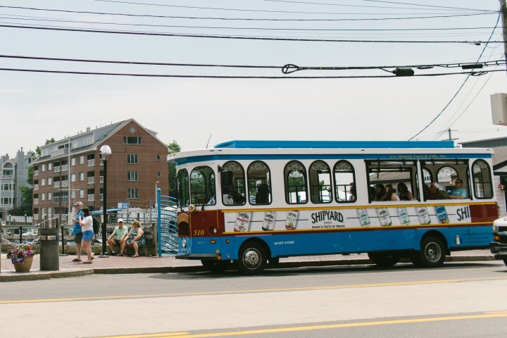 Streetcar passing by a city street with people and buildings in the background.