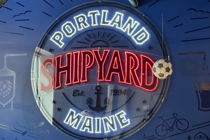 Neon sign reading 'Portland Shipyard Maine' with nautical and brewing imagery.