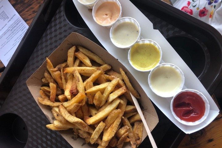 Tray with fries and five dipping sauces in cups.
